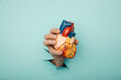 Hand holding heart organ through a hole in a blue background