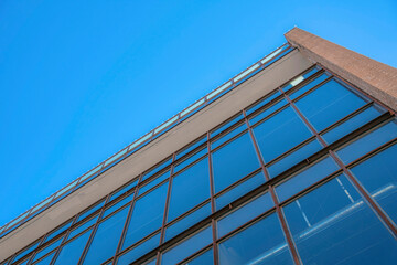 Poster - Modern commercial building lined with glass windows against clear blue sky