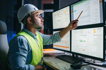 Wall Mural - Worker engineer control process of production uses computer with modern SCADA system which showing AI and machine learning. Bearded operator follow of industry process on factory