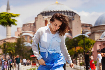 European girl in a blue skirt on the background of a mosque. photo session of a girl on the background of hagia sophia in istanbul. photo of a tourist in istanbul against the backdrop of attractions