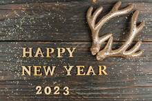 Happy New Year 2023 Quote Made Of Wooden Letters And Golden Reindeer Horns As Decoration. Festive Greeting Card Wor Christmas And New Year Holidays
