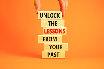 Wall Mural - Lessons from your past symbol. Concept words Unlock the lessons from your past on wooden blocks. Bussinesman hand. Beautiful orange background. Business and lessons from your past concept. Copy space.