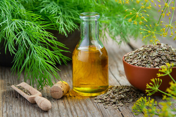 Wall Mural - Bottle of dill seeds oil, bunch of fresh green dill and bowl of dried fennel seeds on wooden board. Alternative herbal medicine. Useful seasoning for cooking.