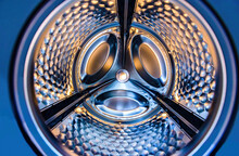 Washing machine drum interior. Perspective inside view into blue washing machine drum moving in fast and quick traffic motion blur