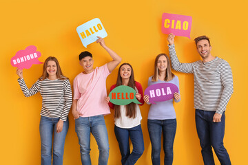 Group of young people holding speech bubbles with words HELLO in different languages on yellow background