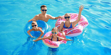 Happy Family Swimming In Pool On Summer Day