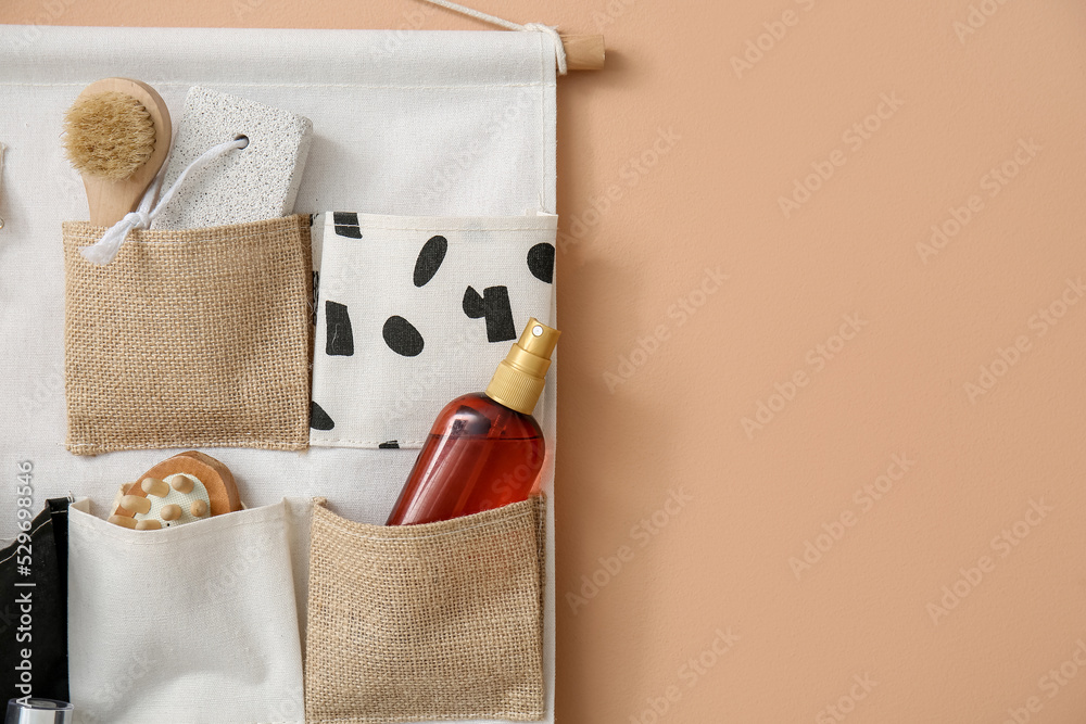 Holder with bath accessories hanging on beige wall, closeup