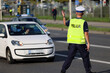 Policjant ruchu drogowego przy swoim radiowozie kontroluje ruch drogowy w mieście.