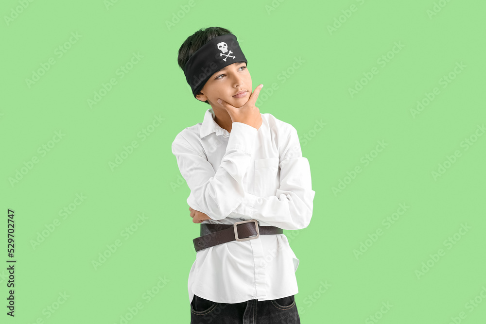 Thoughtful little boy dressed as pirate on green background