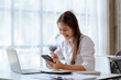 © Kritdanai - Happy young Asian businesswoman sitting on her workplace in the office. Young woman working at laptop computer in the office