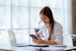 © Kritdanai - Happy young Asian businesswoman sitting on her workplace in the office. Young woman working at laptop computer in the office