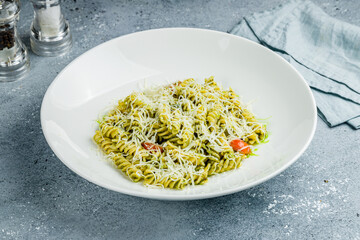 Wall Mural - fusilli pasta with pesto sauce, tomatoes and cheese parmesan on grey table