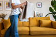 © Daniel - Unrecognisable woman folding blanket tying up living room, cleaning the house.