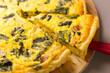 A slice of quiche with bacon and spinach
