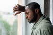 © Prostock-studio - Unhappy frustrated adult african american guy in casual suffering from depression and bad news near window