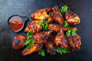 Wall Mural - Traditional barbecue chicken wings and drumsticks with hot chili mango sauce and coriander served as top view on a rustic plate with copy space