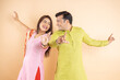 © GAJENDRRA BHATI  - Happy indian couple dancing together wearing traditional or ethnic cloths isolated on studio background, Man and woman celebrating diwali festival, onlie sale, enjoying life concept,