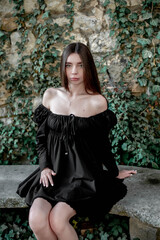 Portrait of a beautiful girl sitting on a stone