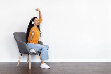 Poster - Emotional young woman sitting at arm chair, listening to music