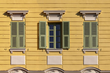 Typical facade in the south of France, on the French Riviera, windows with colored shutters