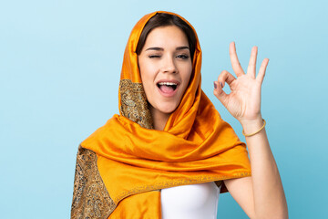 Sticker - Young Moroccan woman with traditional costume isolated on blue background showing ok sign with fingers