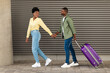 © Prostock-studio - Happy African American Tourists Couple Walking With Suitcase Outdoors