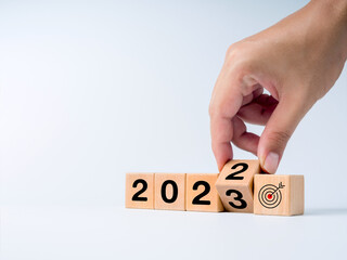 Poster - The calendar year 2022 changed to 2023 with the goal and successful concept. Hand turning wooden cube blocks for the transition from 2022 to 2023 with target icon sign isolated on white background.