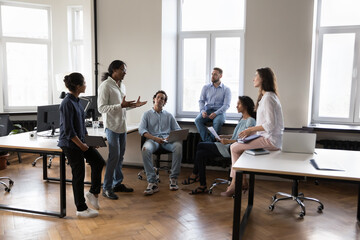 Wall Mural - Indian startup leader man instructing team, speaking before employees on briefing, sharing ideas, presenting solution, Corporate teacher, mentor teaching new diverse interns