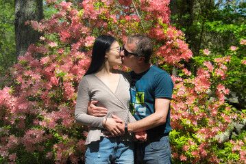 a mixed race couple kissing in a garden