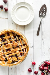 Wall Mural - Top down view of a freshly baked lattice cherry pie with plates for serving.