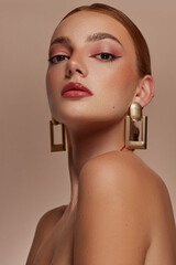 model with red hair, brown eyes and freckles, poses, beauty shoot. she wears gold rectangle earrings