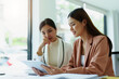 © Jirapong - Two Asian businesswoman using a tablet and documents to work.