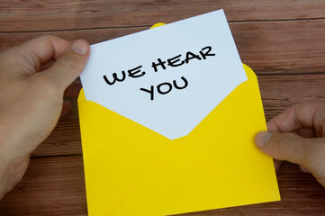 We hear you text on white notepad in yellow envelope. Listening concept