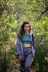 Portrait of romantic woman at fairy forest. A beautiful young girl with glasses is walking through the forest. Girl purple suit. Corduroy fabric