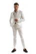sexy young man holding one hand in pocket and opening white suit