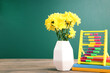Bouquet of chrysanthemums with colorful abacus and notebooks on school chalkboard background with copy space. Concept teachers day