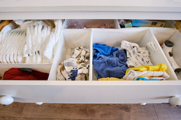 Storage of children s clothes in white chest of drawers, open closet shelf close-up with clothes