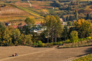 Poster - Tractor on rural field as autumnal hills on background in Italy.