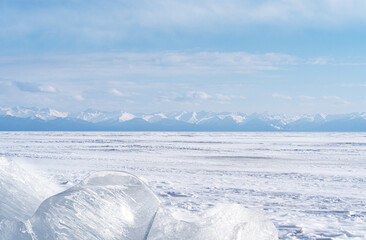 Wall Mural - Winter landscape with ice hummocks glittering in the sun and mountains of Lake Baikal in Siberia at sunset. Natural background.