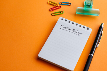 Poster - there is a notebook with the word cookie policy. it's placed on a color background.