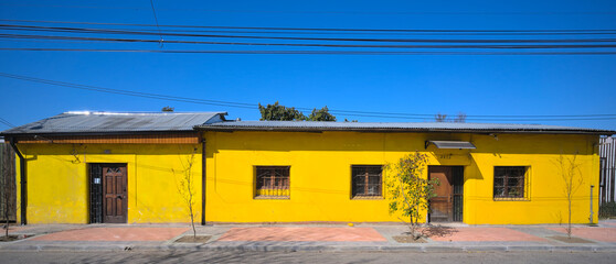 Wall Mural - Facade of a one-floor traditional adobe house in a small south american town under blue sky (Talca, Maule, Chile) 