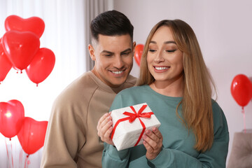 Poster - Lovely couple with gift in room. Valentine's day celebration