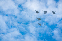 Military Aircraft Flying High In The Blue Sky With Clouds.