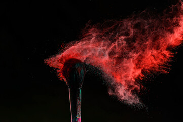 Wall Mural - Makeup brush with an explosion of red powder on a black background.