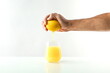 concept of freshly squeezed juice. hand squeezes juice from lemon into a glass. juice flowing into a glass on white background