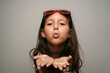 © Westend61 - Cute girl with sunglasses blowing kiss against gray background