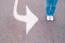 Woman Standing By Arrow Symbol On Road