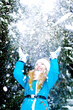A close up of happy little girl throwing up snow in forest.