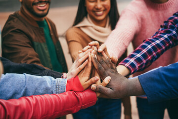 Wall Mural - Young diverse team having fun stacking hands outdoor - Focus on hands