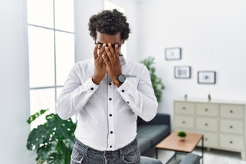 Poster - African psychologist man at consultation office with sad expression covering face with hands while crying. depression concept.